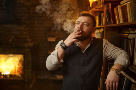 Bearded man holds ashtray and smoking cigaretteの写真素材