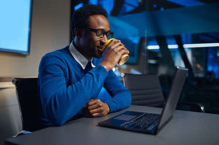 Manager in glasses works on laptop in night offic