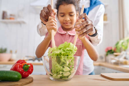 Father and daughter cooking salad on breakfastの写真素材