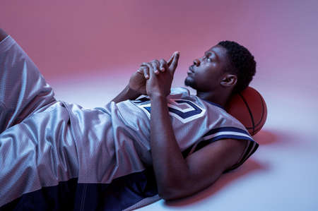 Basketball player lying with ball in studioの写真素材