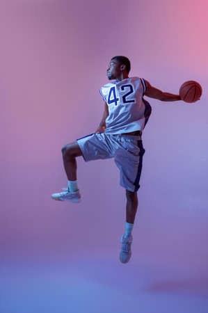 Basketball player jumping with ball in studioの写真素材