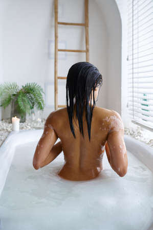 Attractive woman relax in a bubble bath, back view
