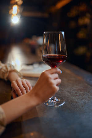 Woman with glass of wine sitting at counter in barの写真素材