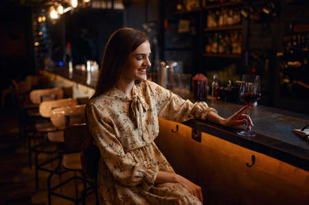 Alone woman with glass of wine sitting in barの写真素材