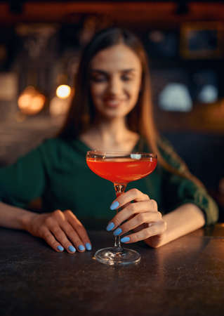 Smiling woman drinks coctail at the counter in barの写真素材