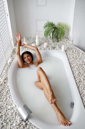 Young happy woman, relaxation in bath with milkの写真素材