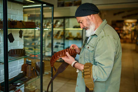 Bearded hunter choosing bandolier in gun store