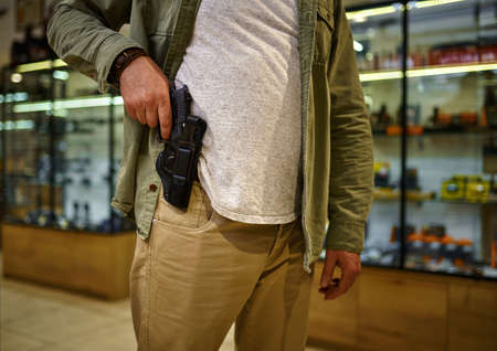 Man pulls a pistol from a holster in gun storeの写真素材