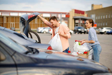 Family couple puts their purchases in the trunk