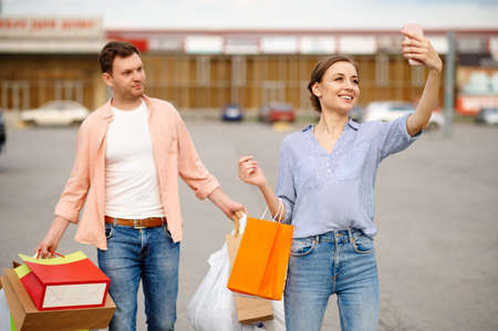 Family couple with bags makes selfie on parking