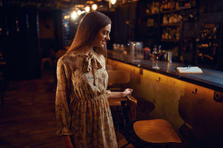 Alone woman with glass of wine sitting in bar