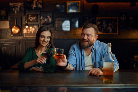 Happy couple drinks alcohol at the counter in barの写真素材