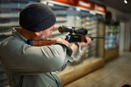 Hunter buying rifle with optical sight, gun storeの写真素材