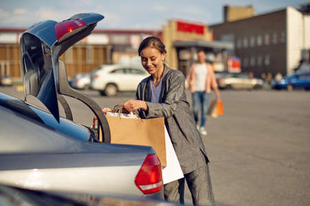 Woman puts her purchases in the trunk on parkingの写真素材