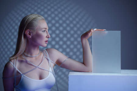 Futuristic young woman near blur glass on cube