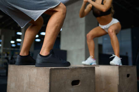 Slim couple doing balance exercise on cubes in gymの写真素材