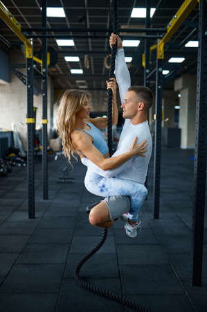 Love couple is hanging on a rope, training in gym