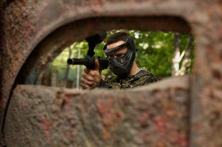 Paintball player in uniform and mask in forestの写真素材