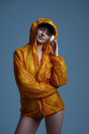 Futuristic woman in raincoat, cap and headphonesの写真素材