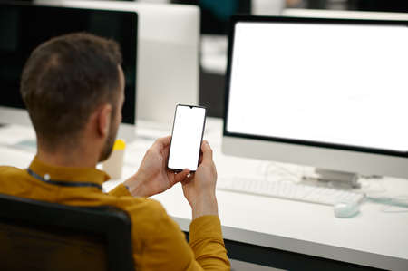 Male manager using phone in IT officeの写真素材