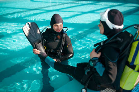 Male instructor helps woman to put on fins, divingの写真素材