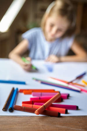 Little girl drawing with markers, kid in workshop