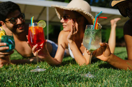 Cheerful friends with coctails rest on the grassの写真素材