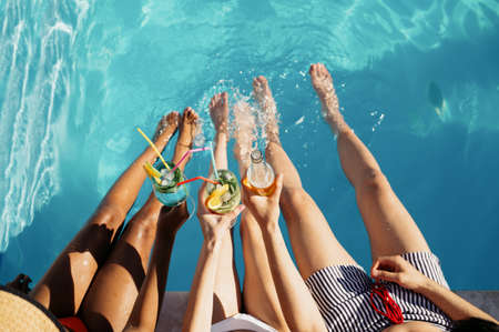 Friends drink beverages at the pool, top view