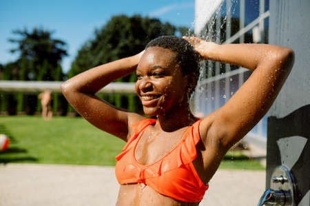 Sexy woman in swimsuit takes a shower at the poolの写真素材