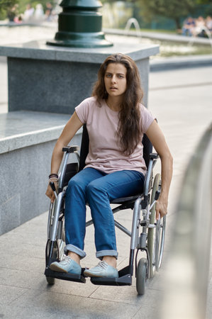 Disabled woman in wheelchair climbs the rampの写真素材