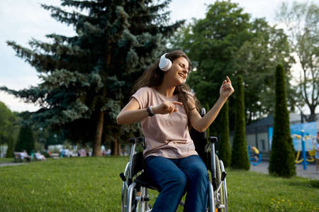 Disabled woman in wheelchair listens to musicの写真素材