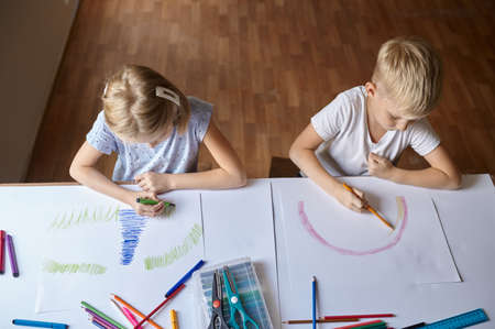 Two children drawing at the table, top viewの写真素材