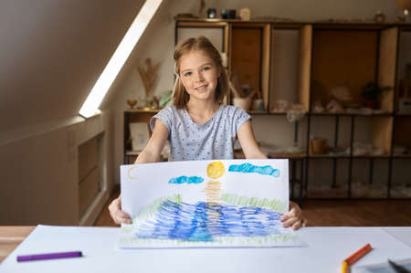 Little girl shows her drawing, kid in workshopの写真素材