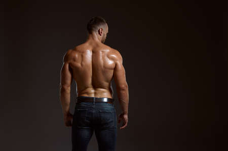 Male athlete with muscular body poses in studio