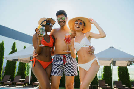 Friends with coctails pose at the pool in hotelの写真素材