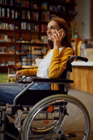 Disabled female student in wheelchair using phoneの写真素材