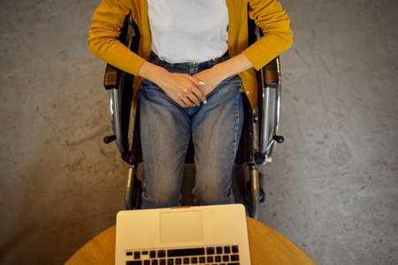 Disabled female student in wheelchair using laptopの写真素材