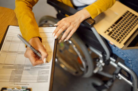 Disabled student in wheelchair writes in notebook