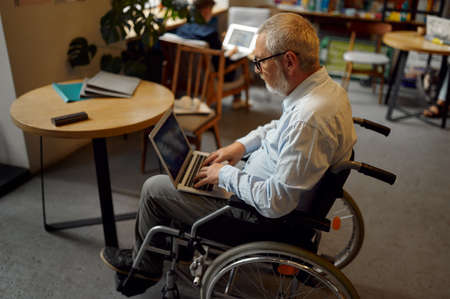 Adult disabled man using laptop, top viewの写真素材