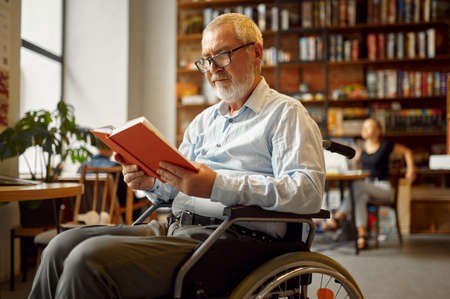 Adult disabled man in wheelchair reading a bookの写真素材