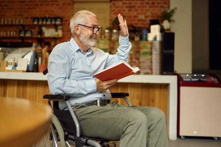Adult disabled man in wheelchair reading a bookの写真素材
