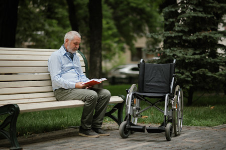 Adult disabled man with wheelchair sits on a benchの写真素材