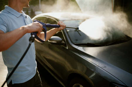 Man holds high pressure water gun, hand car washの写真素材