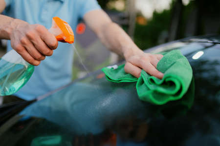 Man using window cleaner and a rag, hand auto wash