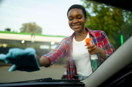 Woman wipes car window with a rag, hand auto washの写真素材