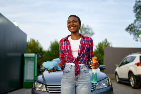 Woman poses with spray and a rag, car wash stationの写真素材