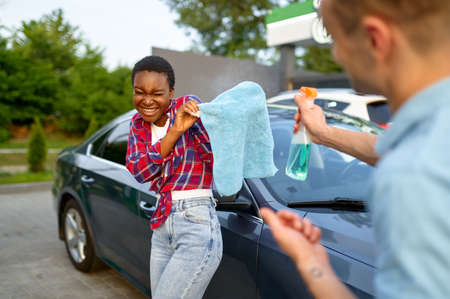 Man and woman having fun on hand car wash stationの写真素材