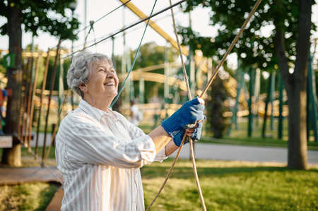 Pretty granny climbing on ropes in summer parkの写真素材