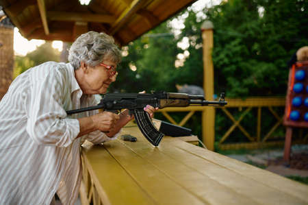 Grandma with gun poses in shooting galleryの写真素材