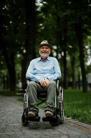Adult disabled man in wheelchair holds paper sheetの写真素材